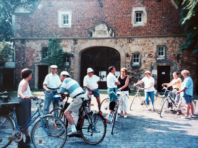 Auf dem Foto sind mehrere Radfahrerinnen und Radfahrer vor einem historischen Gebäude zu sehen.