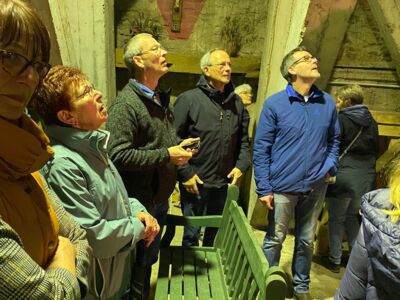 Mehrere Teilnehmer im Kirchturm schauen zu den Glocken auf.